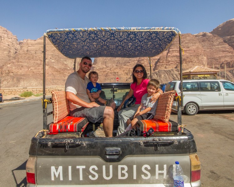 A family in the back of a covered pickup truck on a Wadi Rum Jeep Tour